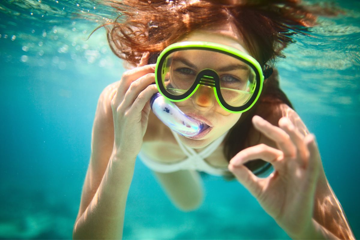 Femme rousse avec masque et tuba qui pratique le snorkeling